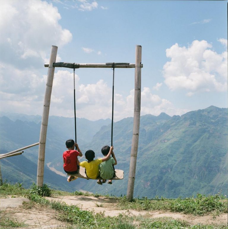 Children on a Swing on the Edge of a Mountain
